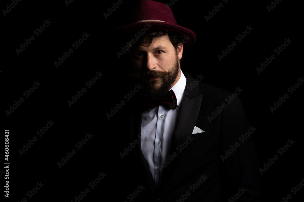 businessman posing in the dark and wearing a burgundy hat businessman posing in the dark and wearing a burgundy hat