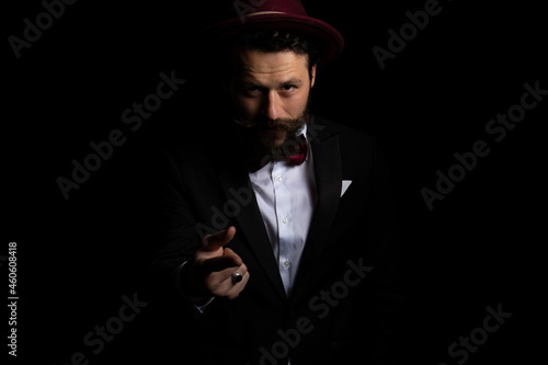 businessman pointing at the camera and wearing a burgundy hat