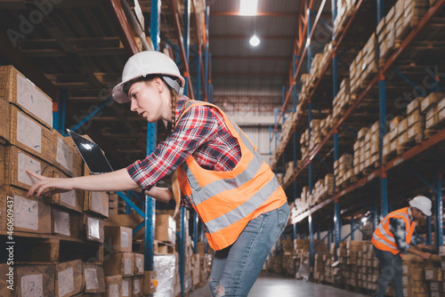 Logistic woman worker staff in safety suit holding computer laptop working in warehouse store