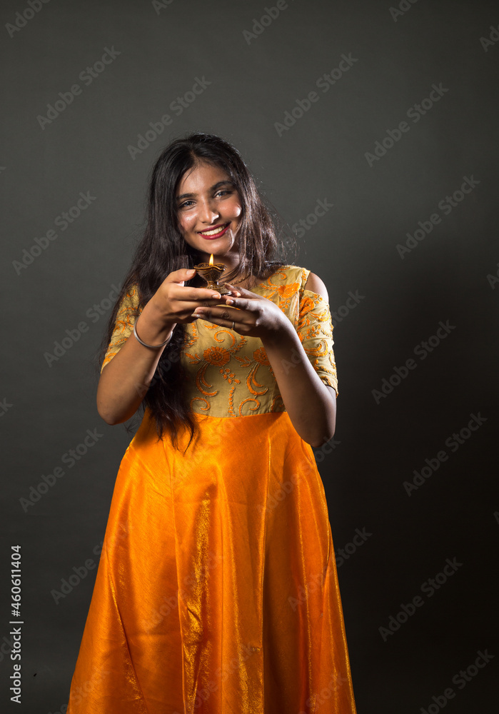 Beautiful Indian Girl in indian Traditional dress holding Diwali diya(oil Lamp) over gray background. Greetings happy diwali. Diwali is a hindu festival of lights and happiness Beautiful Indian Girl in indian Traditional dress holding Diwali diya(oil Lamp) over gray background. Greetings happy diwali. Diwali is a hindu festival of lights and happiness