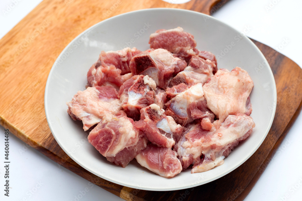 Raw pork ribs in white plate on cutting board on white background. Raw pork ribs in white plate on cutting board on white background.