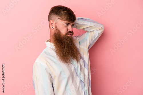 Young caucasian ginger man with long beard isolated on pink background tired and very sleepy keeping hand on head.