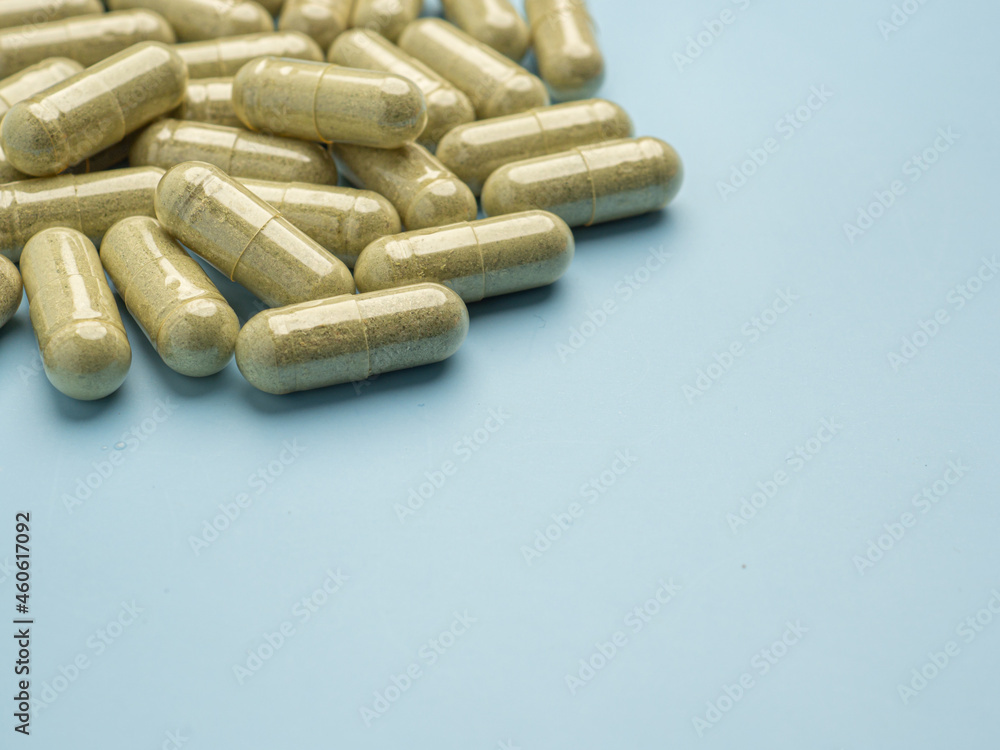 Top view of Andrographis paniculata capsules isolated on light blue background. Space for text. Herbal, medicine, and healthcare concept Top view of Andrographis paniculata capsules isolated on light blue background. Space for text. Herbal, medicine, and healthcare concept