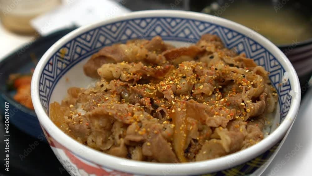 pouring shichimi or Japanese spice on beef bowl with miso soup pouring shichimi or Japanese spice on beef bowl with miso soup