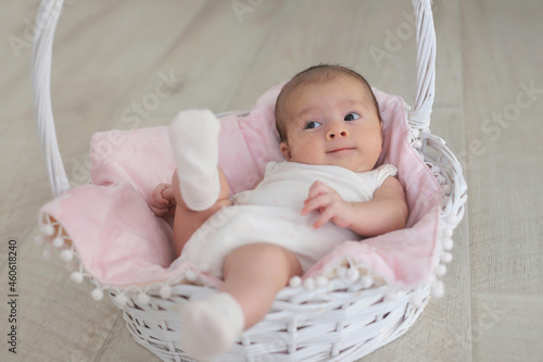 Smiling baby is lying in a white basket.