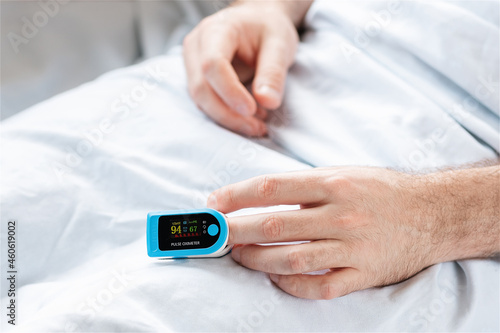Patient lying at bed with pulse oximeter. Close up of hands. Concept of determination of oxygen in the blood. Treatment in the intensive care unit