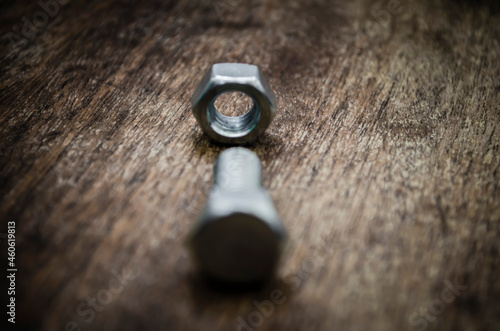 Metal bolt and nut on old wooden background stylized blur background