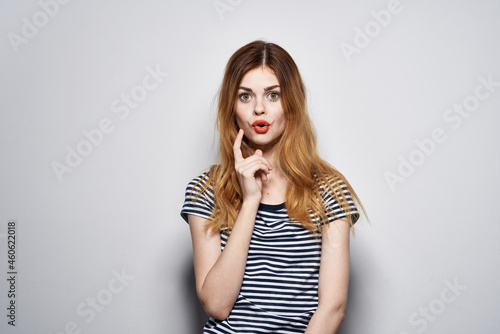 beautiful woman in a striped t-shirt gesture with his hands light background