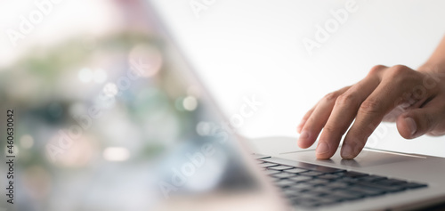 young man hand working on a laptop, bokeh blurred at natural For text copy space, image size horizontal.