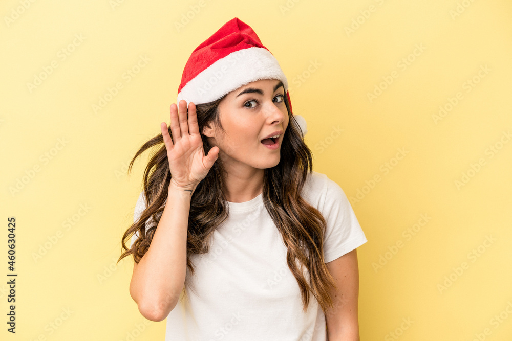 Young caucasian woman celebrating Christmas isolated on yellow background trying to listening a gossip. Young caucasian woman celebrating Christmas isolated on yellow background trying to listening a gossip.
