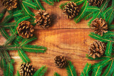 Christmas background. Spruce branches in the form of a round frame and pinecones on a wooden background