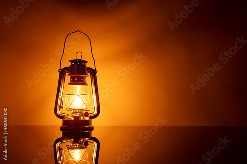 Burning yellow kerosene lamp background with reflection, concept lighting