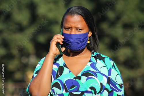 portrait of a masked woman talking with her mobile phone cell phone