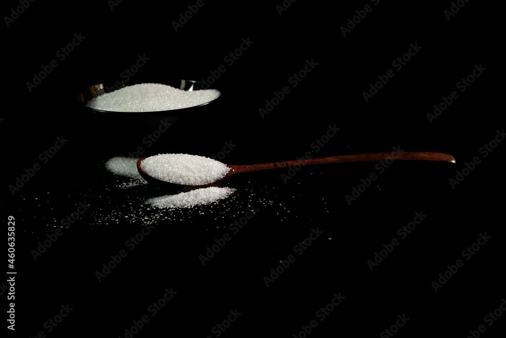 Sugar,Spoon with white sugar on a black background Sugar,Spoon with white sugar on a black background