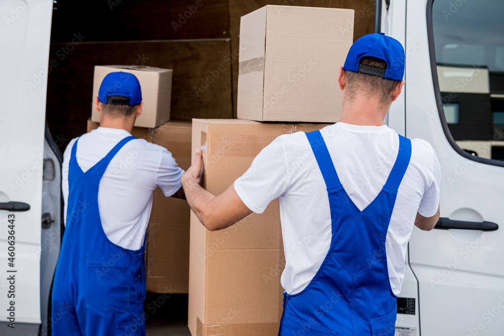 Two removal company workers unloading boxes from minibus into new home Two removal company workers unloading boxes from minibus into new home
