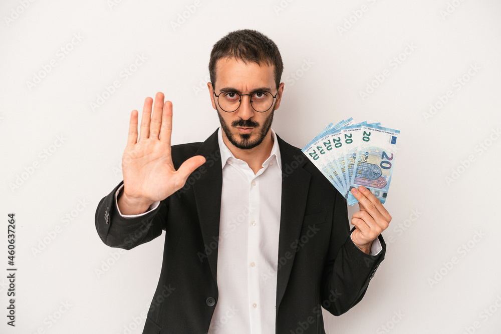 Young caucasian business man holding banknotes isolated on white background standing with outstretched hand showing stop sign, preventing you. Young caucasian business man holding banknotes isolated on white background standing with outstretched hand showing stop sign, preventing you.