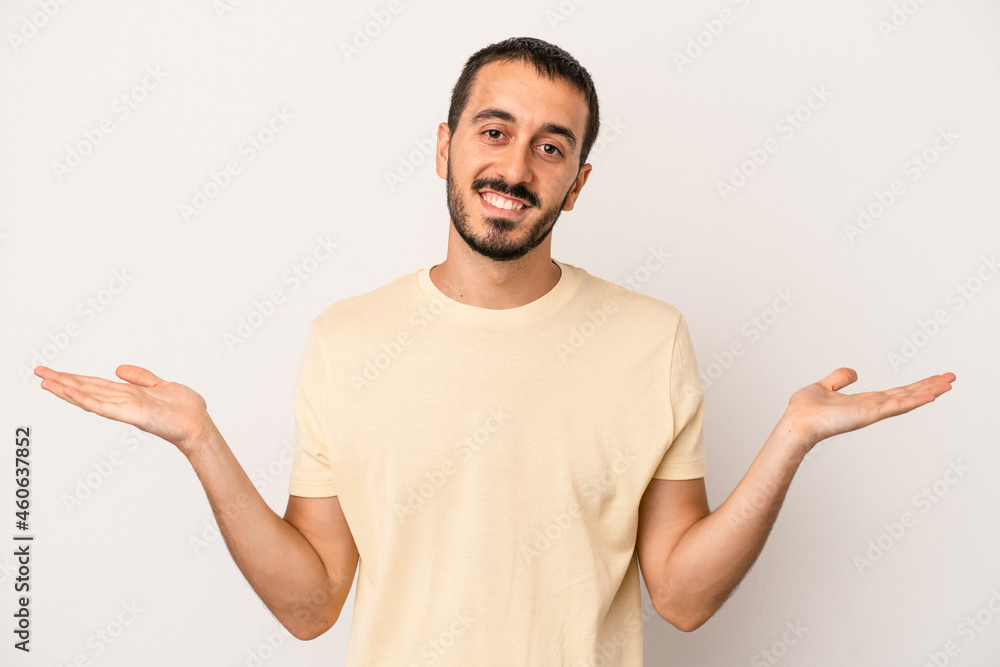 Young caucasian man isolated on white background makes scale with arms, feels happy and confident. Young caucasian man isolated on white background makes scale with arms, feels happy and confident.