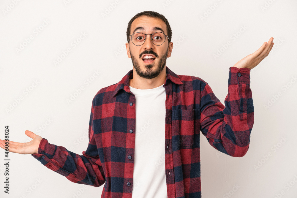 Young caucasian man isolated on white background holds copy space on a palm, keep hand over cheek. Amazed and delighted. Young caucasian man isolated on white background holds copy space on a palm, keep hand over cheek. Amazed and delighted.