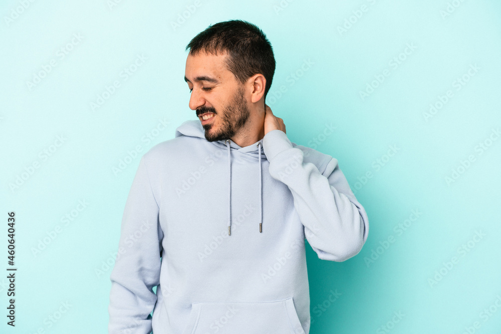 Young caucasian man isolated on blue background having a neck pain due to stress, massaging and touching it with hand. Young caucasian man isolated on blue background having a neck pain due to stress, massaging and touching it with hand.