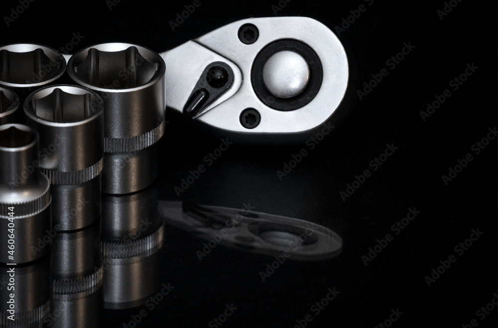 Ratchet wrench. Set of stainless steel hex sockets on shiny black surface. Universal professional tool for car repair. Low key photo. Ratchet wrench. Set of stainless steel hex sockets on shiny black surface. Universal professional tool for car repair. Low key photo.