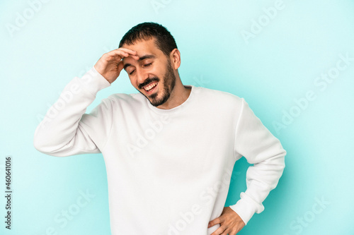 Young caucasian man isolated on blue background joyful laughing a lot. Happiness concept.