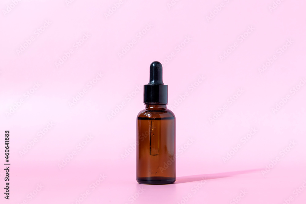 Brown glass bottle with dropper on pink background. Serum or essential oil packaging. Cosmetic product mockup.Copy space. Brown glass bottle with dropper on pink background. Serum or essential oil packaging. Cosmetic product mockup.Copy space.