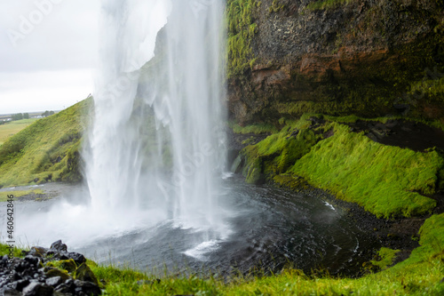 beautiful view of an Icelandic water fall during a cloudy day. The Skogafoss waterfall is a tourist attraction that brings in many visitors 