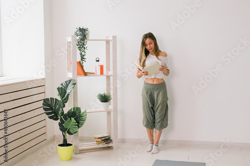 Young woman looking photo album at home. Memories and leisure concept.