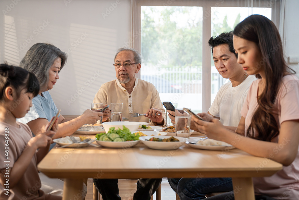 Asian Addicted family use mobile phone while eating breakfast on table. Asian Addicted family use mobile phone while eating breakfast on table.