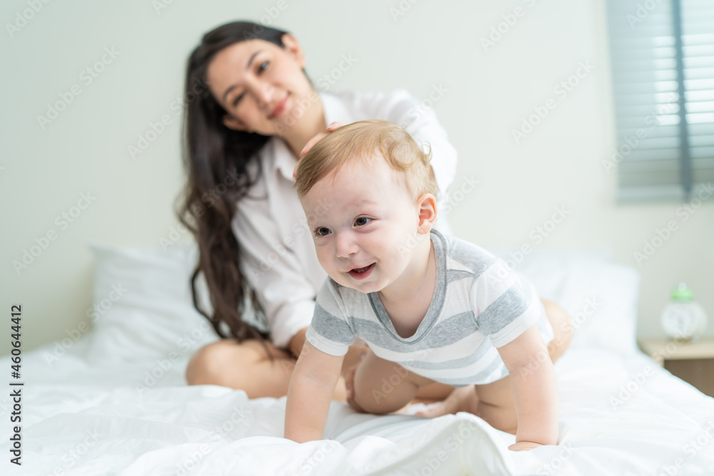 Caucasian mother play with cute baby boy child on infant bed at home. Caucasian mother play with cute baby boy child on infant bed at home.