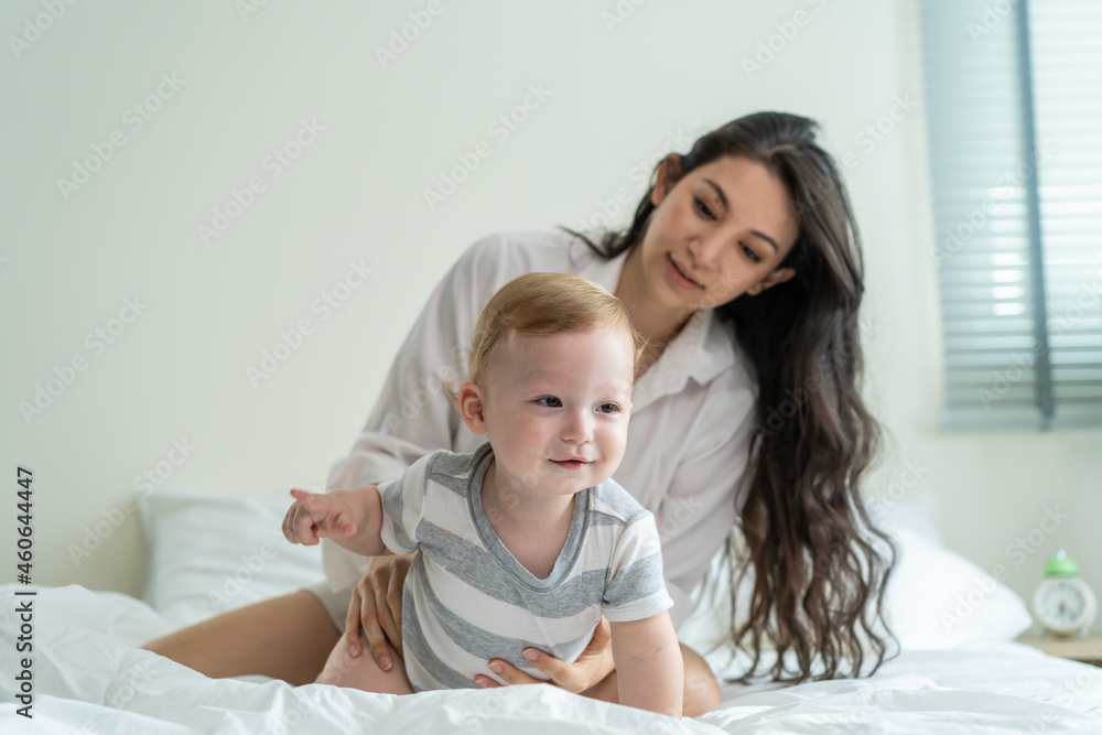 Caucasian mother play with cute baby boy child infant on bed at home. Caucasian mother play with cute baby boy child infant on bed at home.