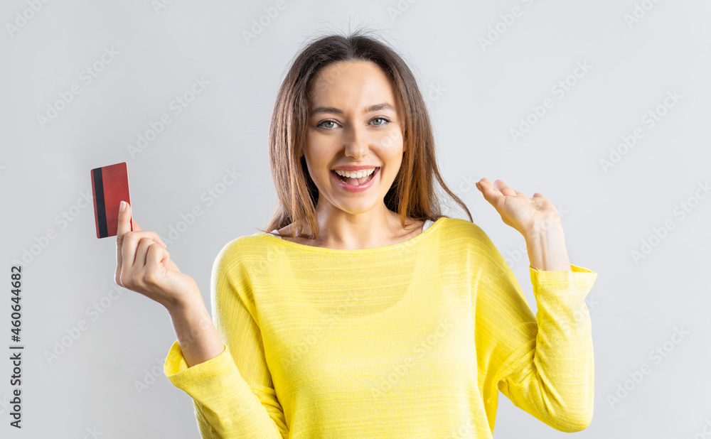 Cheerful young woman holding credit card and looking at camera.