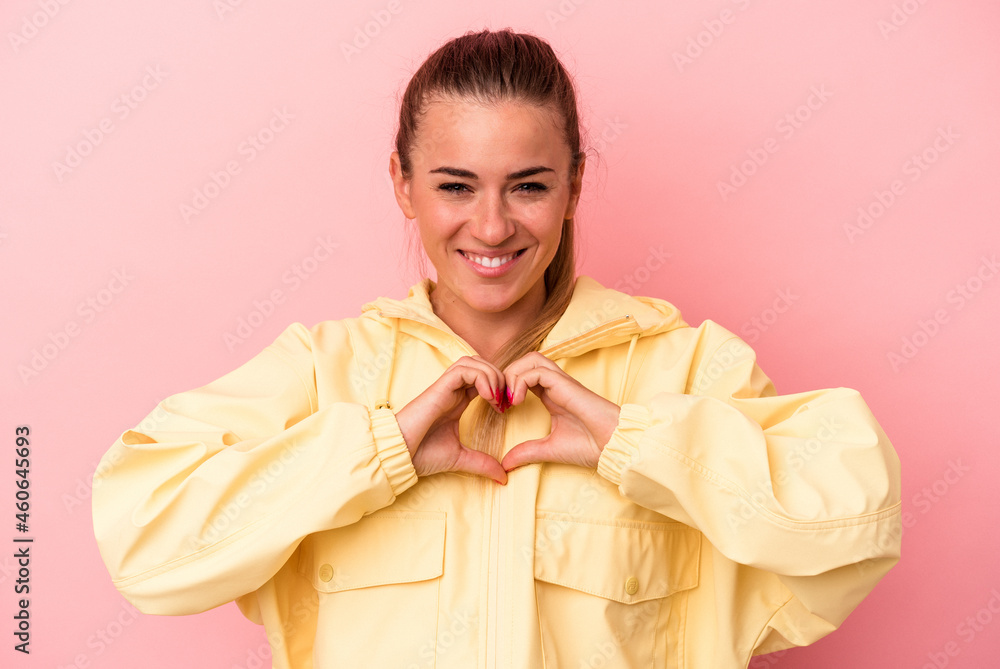 Young Russian woman isolated on pink background smiling and showing a heart shape with hands. Young Russian woman isolated on pink background smiling and showing a heart shape with hands.