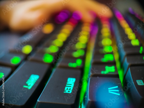 Gamer keyboard with neon backlight macro defocused close up. Online games and virtual reality concept background.