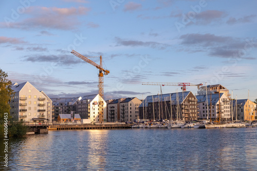 A view of appartment buildings being built near the lake with boats and yacht in the front.
