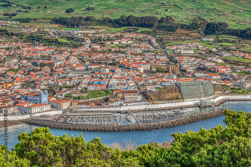 Overview from above of colorful buildings of historic Angra do Heroismo,  marina, and green farmland  as seen from Monte Brasil, Terceira, Azores. photo