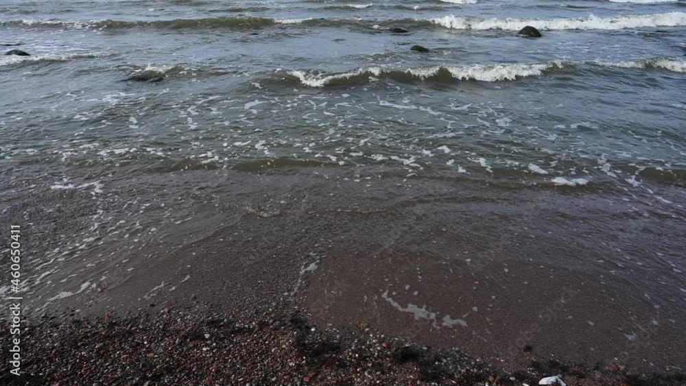 Pebble stones on the sea beach, the rolling waves of the sea with foam Pebble stones on the sea beach, the rolling waves of the sea with foam