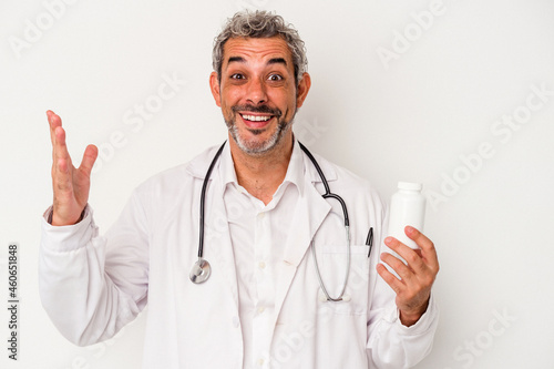 Middle age doctor caucasian man isolated on white background receiving a pleasant surprise, excited and raising hands.