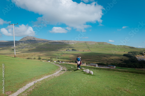 Walkers on Twistleton Lane, a roman road, with landscape views of Ingleborough Peak and White Scar Cave in the Yorkshire Dales