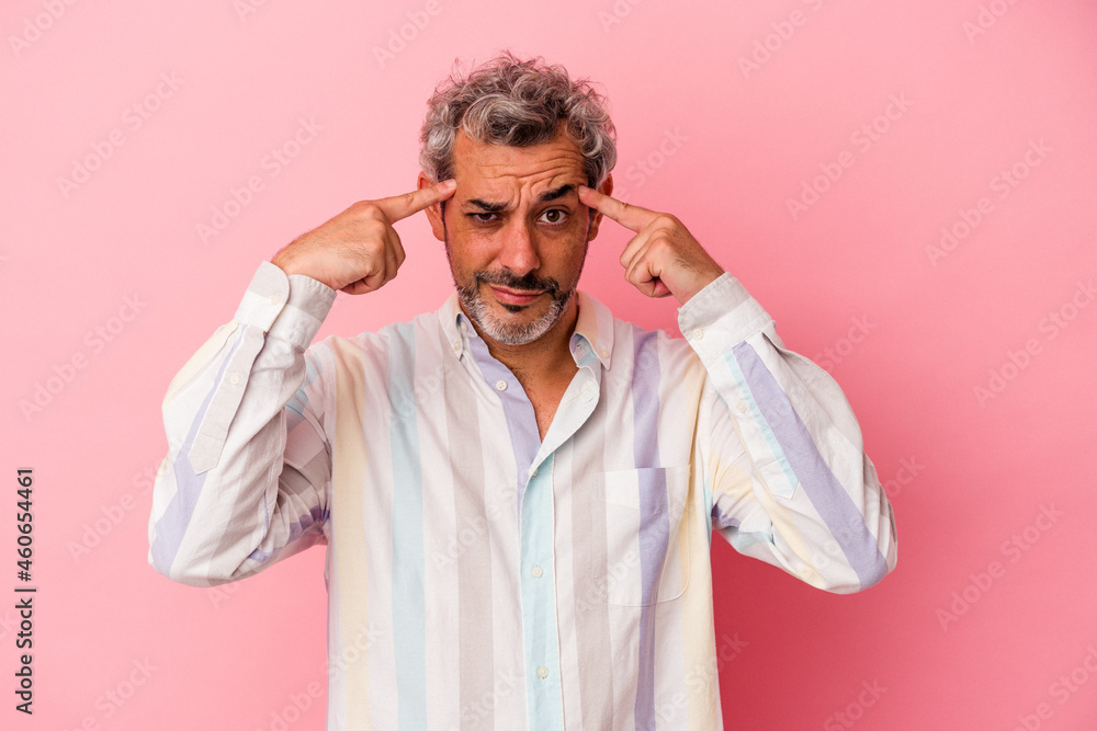 Middle age caucasian man isolated on pink background focused on a task, keeping forefingers pointing head. Middle age caucasian man isolated on pink background focused on a task, keeping forefingers pointing head.