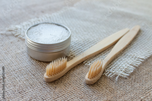 Two natural bamboo toothbrushes and kaolin dentifrice or organic tooth powder made with natural ingredients on rustic background with copy space, selective focus photo