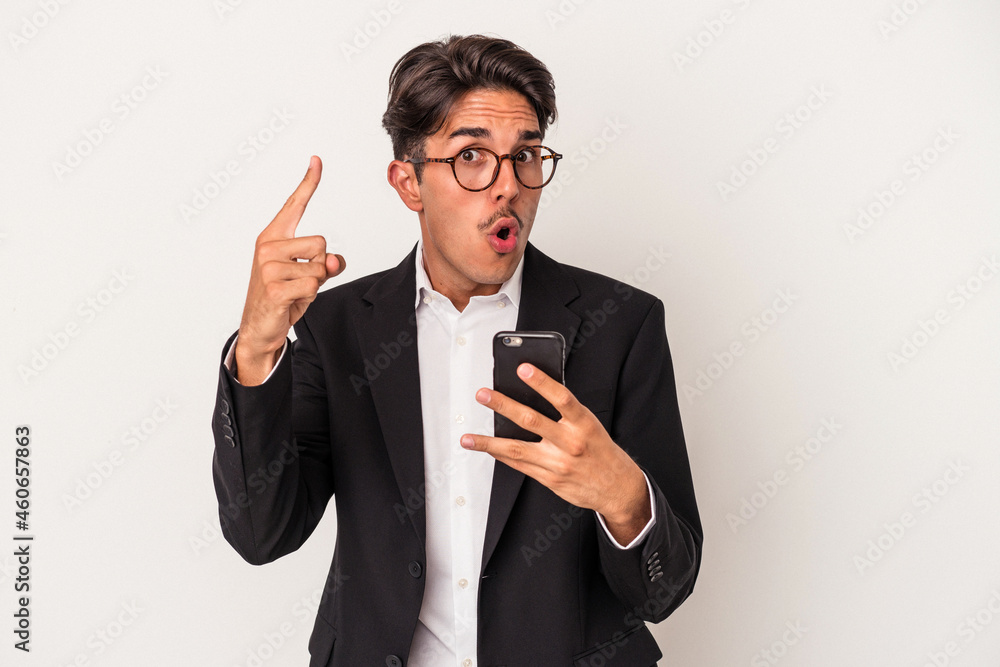 Young mixed race business man holding mobile phone isolated on white background having an idea, inspiration concept. Young mixed race business man holding mobile phone isolated on white background having an idea, inspiration concept.