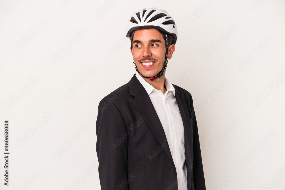 Young mixed race business man wearing a bike helmet isolated on white background looks aside smiling, cheerful and pleasant. Young mixed race business man wearing a bike helmet isolated on white background looks aside smiling, cheerful and pleasant.