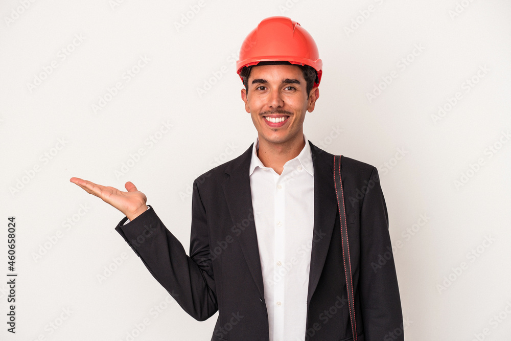Young architect mixed race man isolated on white background showing a copy space on a palm and holding another hand on waist. Young architect mixed race man isolated on white background showing a copy space on a palm and holding another hand on waist.