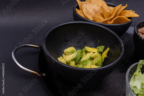 Bowls of tortilla chips and chopped avocado on Mexican comal