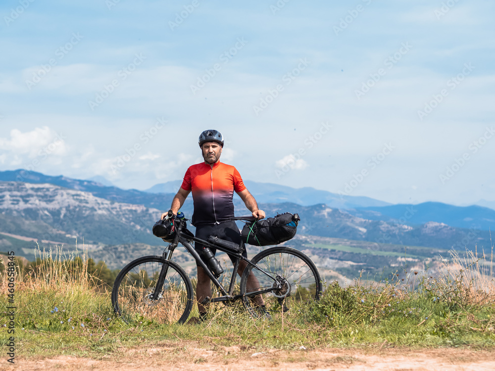 Fototapeta premium Traveler cyclist man looking at camera with a bicycle in nature. Bikepacking 