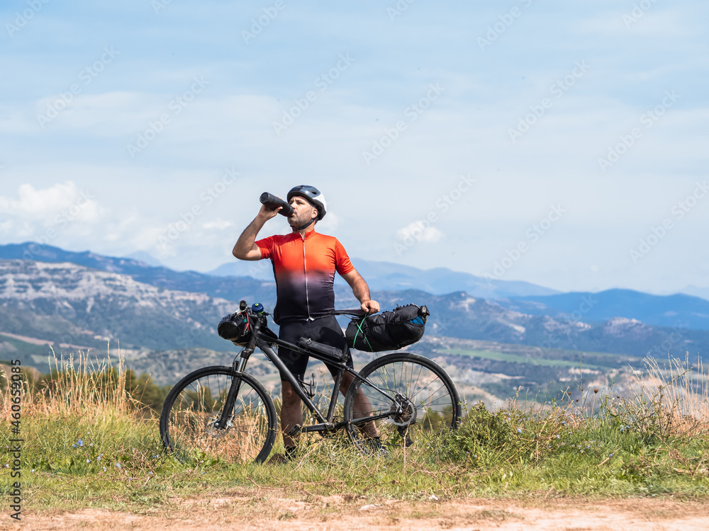 Male cyclist traveler drinks water resting in nature .Bikepacking 