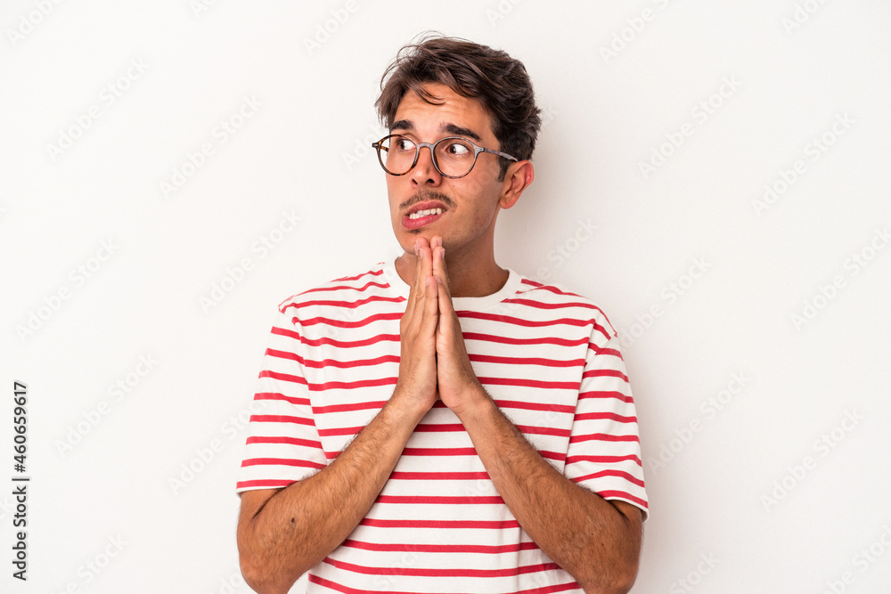 Young mixed race man isolated on white background praying, showing devotion, religious person looking for divine inspiration. Young mixed race man isolated on white background praying, showing devotion, religious person looking for divine inspiration.