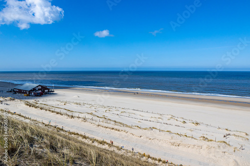Beach with a building  people in the distance with the sea and the horizon in the background  sunny spring day with a blue sky in Petten aan Zee  Noord-Holland in the Netherlands