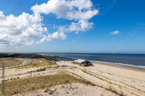 Paths  marram grass and the beach with a building with the sea and the horizon in the background  sunny spring day with a blue sky in Petten aan Zee  Noord-Holland in the Netherlands